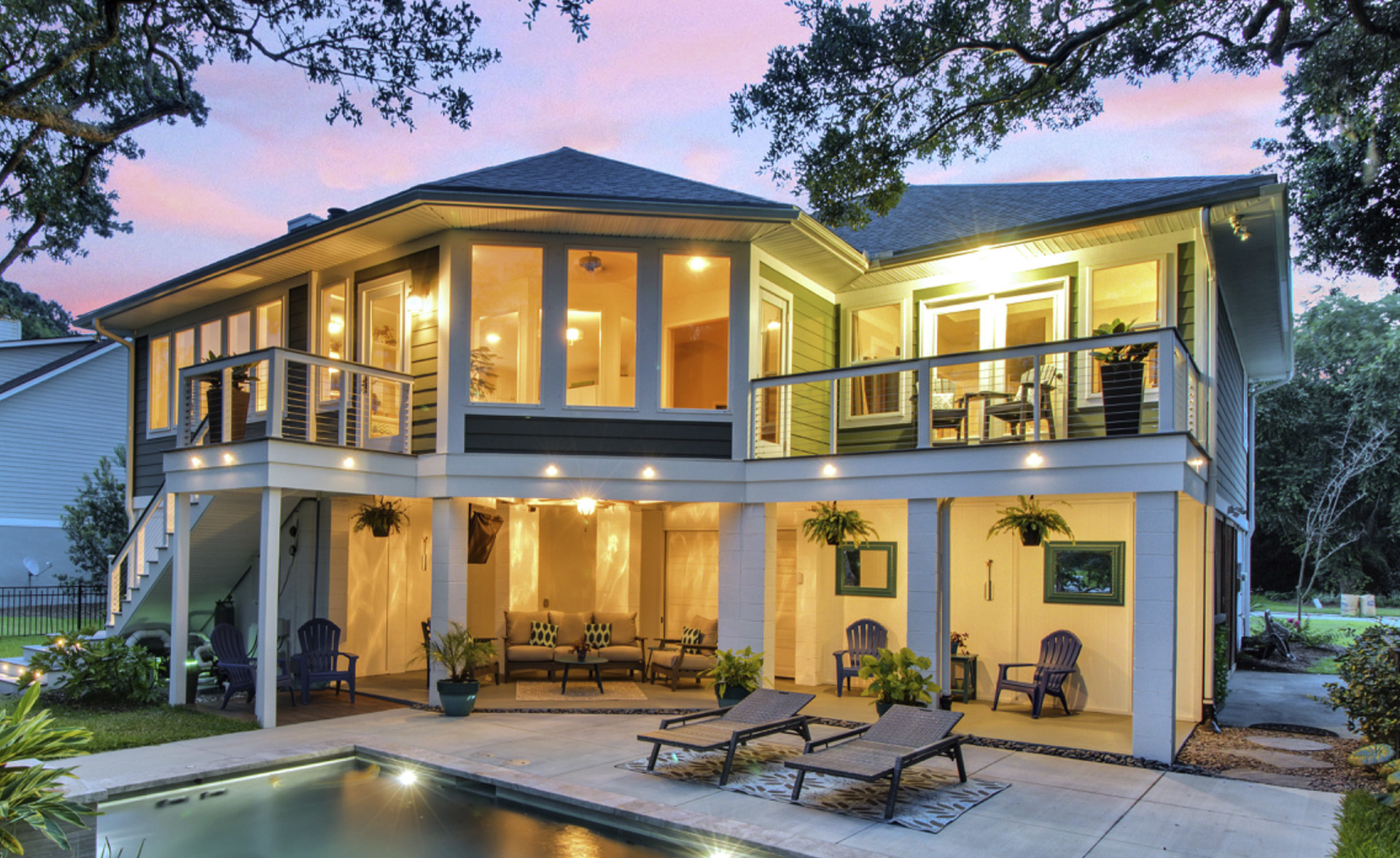 Modern two-story house with a pool, deck, balcony, and outdoor seating.
