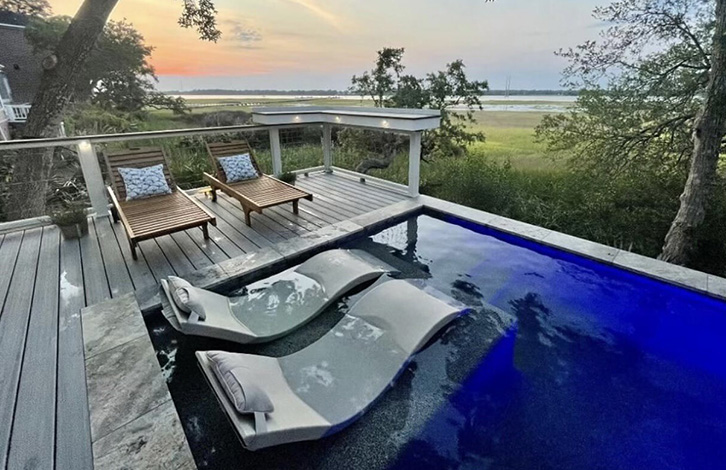 Sunset view from a deck with a small pool and lounge chairs.